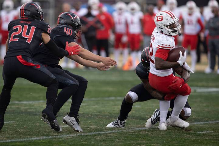 DC Defenders wide receiver Jaquez Ezzard is tackled as Vegas Vipers defenders Will Adams and Ad ...