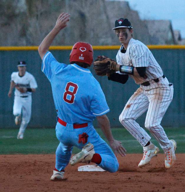 Liberty’s Jacob Damore slides to second base as Desert Oasis’ Ryan Martin throws ...