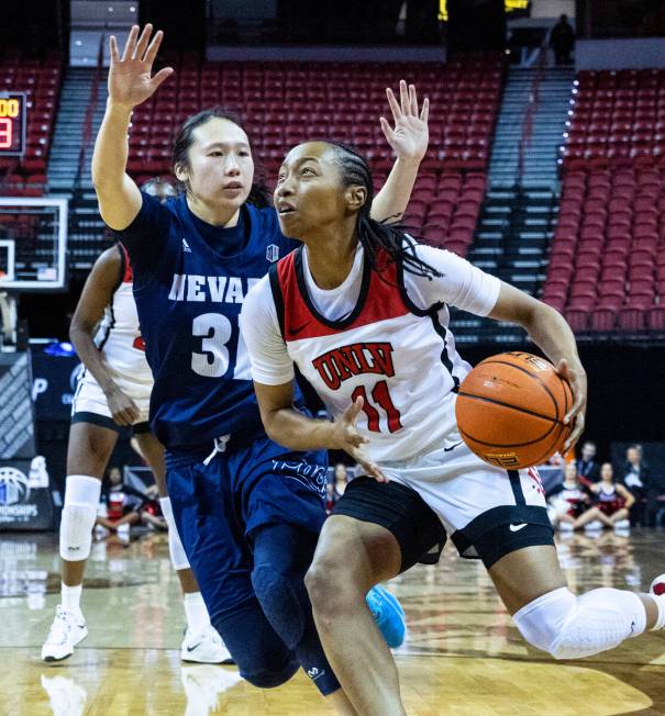 UNLV Lady Rebels guard Justice Ethridge (11) drives past Nevada Wolf Pack guard Tiffany Siu (31 ...