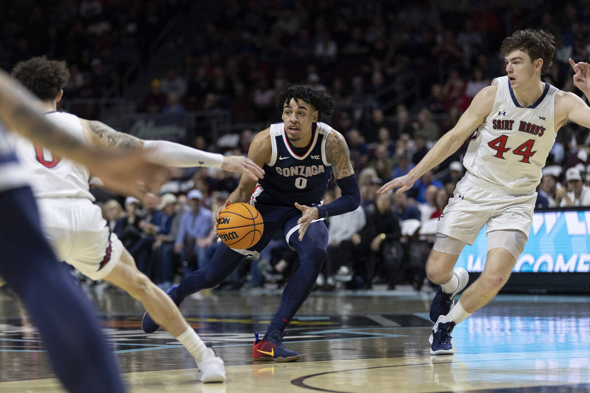 Gonzaga Bulldogs dribbles between St. Mary's Gaels guard Logan Johnson (0) and guard Alex Ducas ...