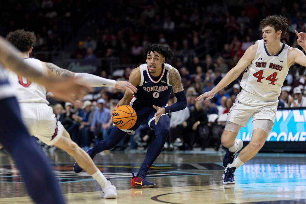 Gonzaga Bulldogs dribbles between St. Mary's Gaels guard Logan Johnson (0) and guard Alex Ducas ...