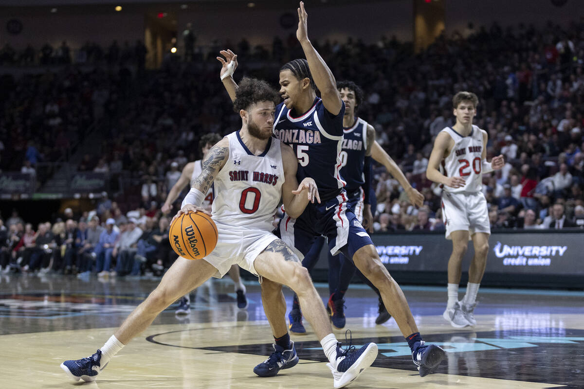 St. Mary's Gaels guard Logan Johnson (0) drives around Gonzaga Bulldogs guard Rasir Bolton (45) ...