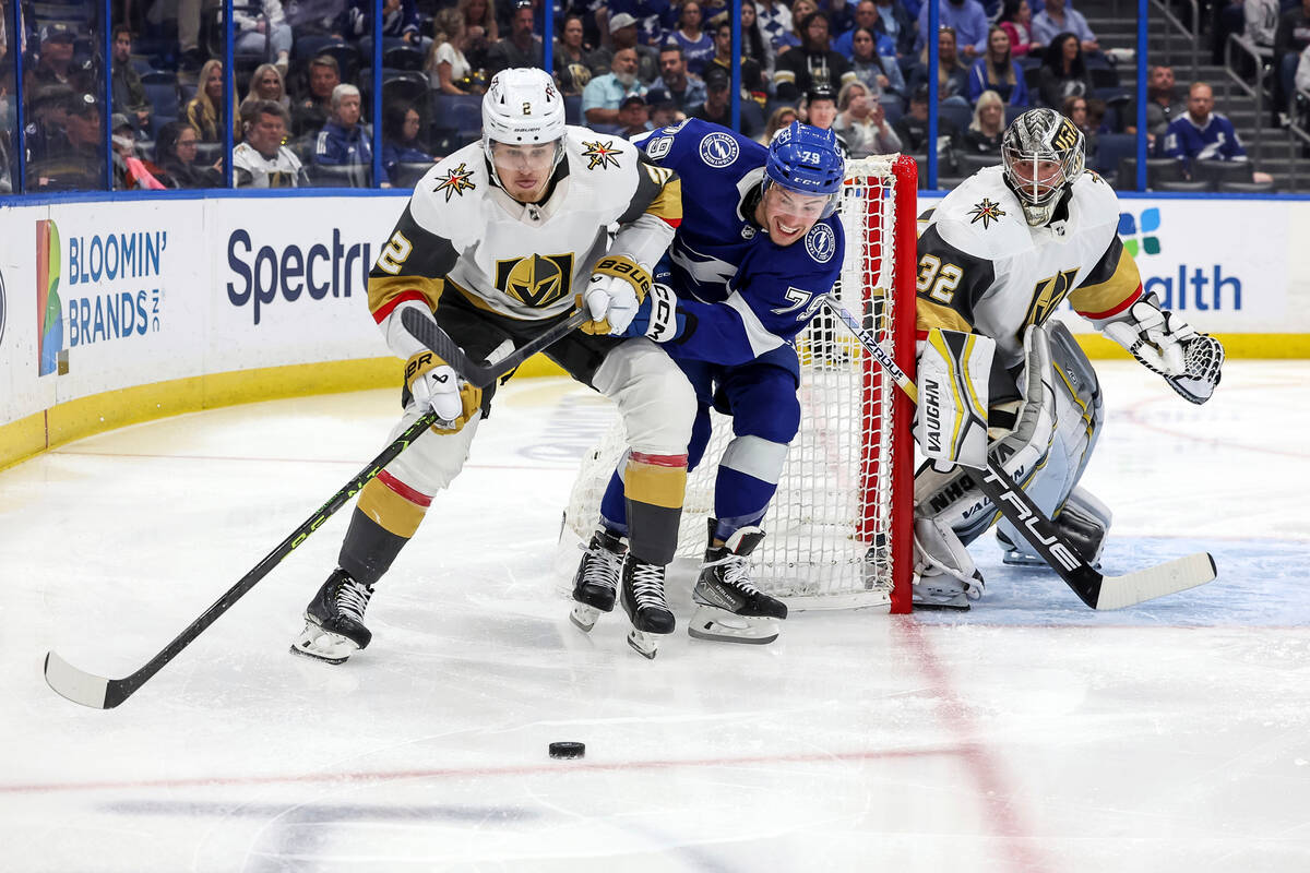 Vegas Golden Knights' Zach Whitecloud (2) avoids the check of Tampa Bay Lightning's Ross Colton ...