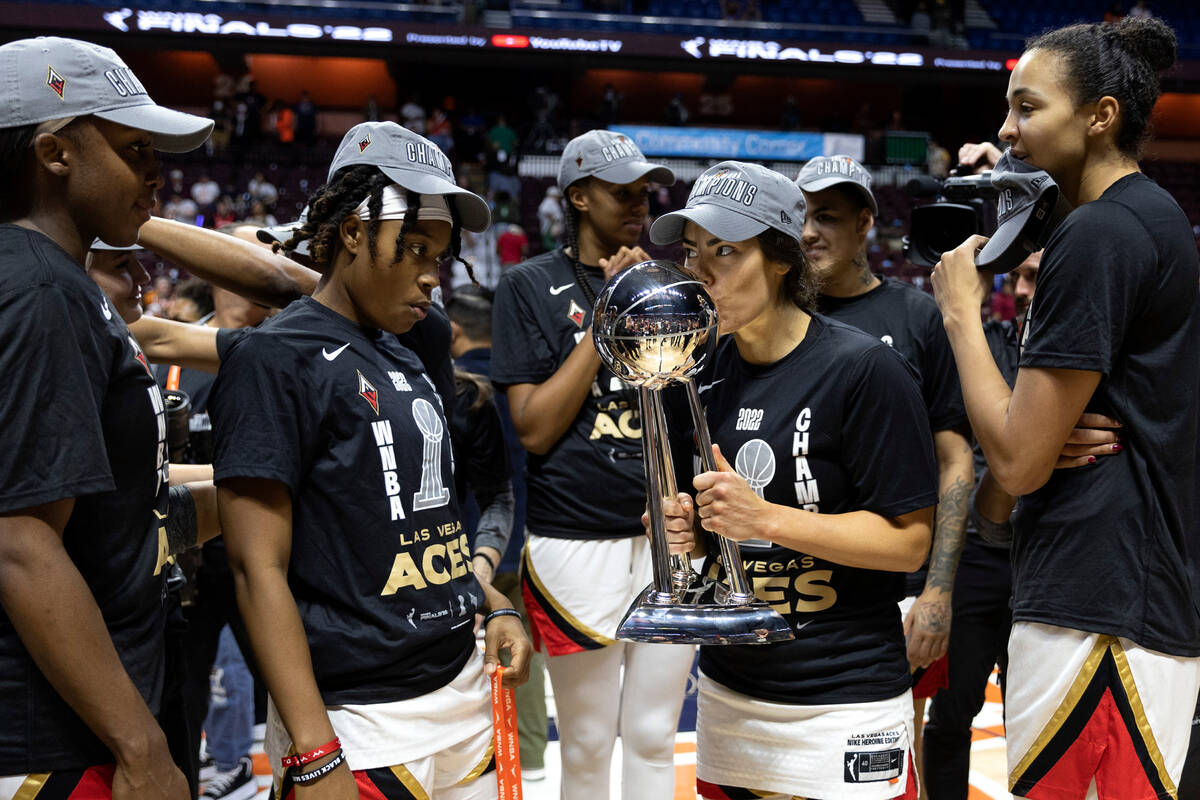 Las Vegas Aces guard Kelsey Plum (10) kisses the 2022 WNBA Championship trophy while teammates ...