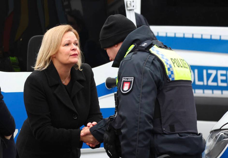 Germany's Interior Minister Nancy Faeser, left, shakes hands with a police officer in Hamburg, ...