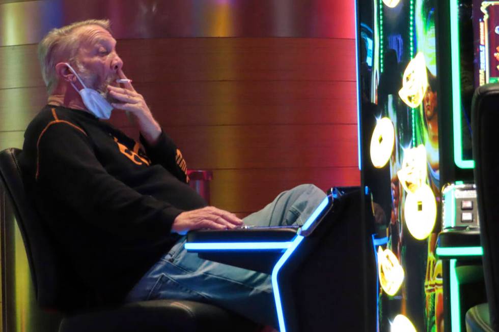 A gambler plays a slot machine while smoking in the Ocean Casino Resort in Atlantic City N.J. o ...