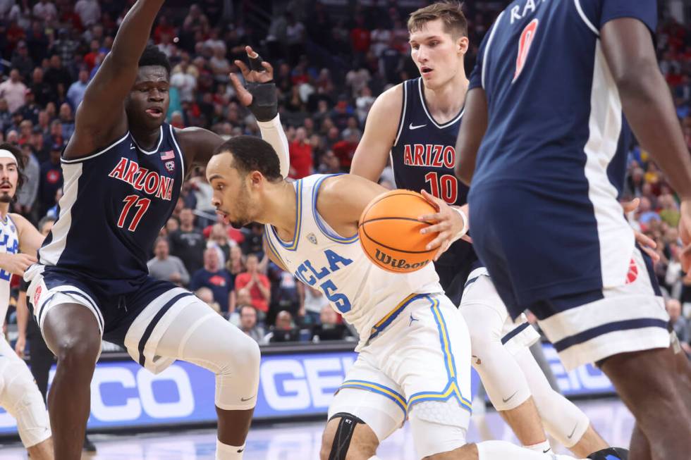 UCLA guard Amari Bailey (5) drives to the basket between Arizona center Oumar Ballo (11) and fo ...