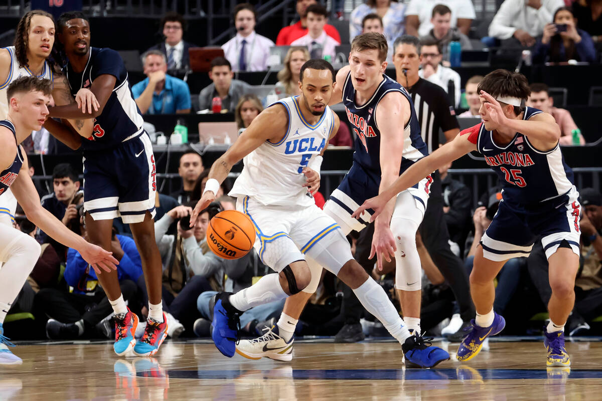 UCLA guard Amari Bailey (5) drives the ball under pressure from Arizona forward Azuolas Tubelis ...