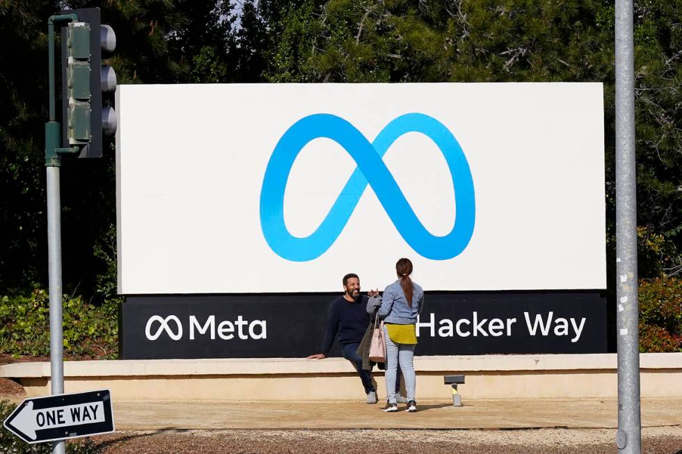 People talk near a Meta sign outside of the company's headquarters in Menlo Park, Calif., Tuesd ...