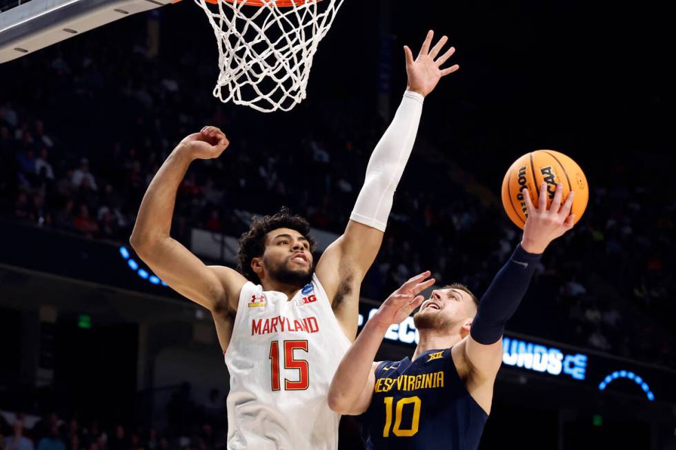 West Virginia guard Erik Stevenson (10) shots as Maryland forward Patrick Emilien (15) defends ...