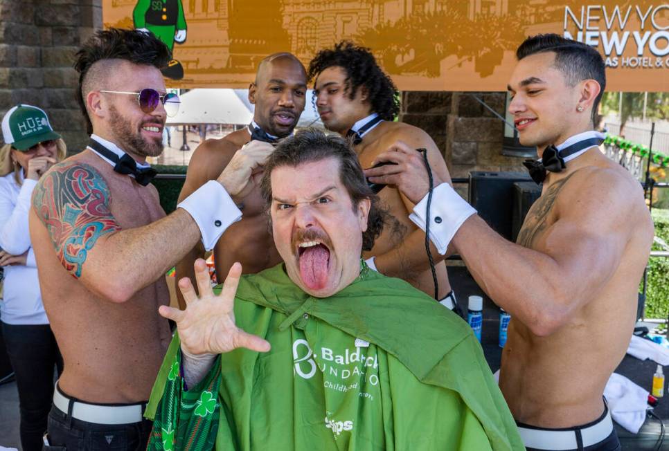 Celebrity Shaver Enoch Augustus Scott of Zombie Burlesque, center, has his head shaved by membe ...