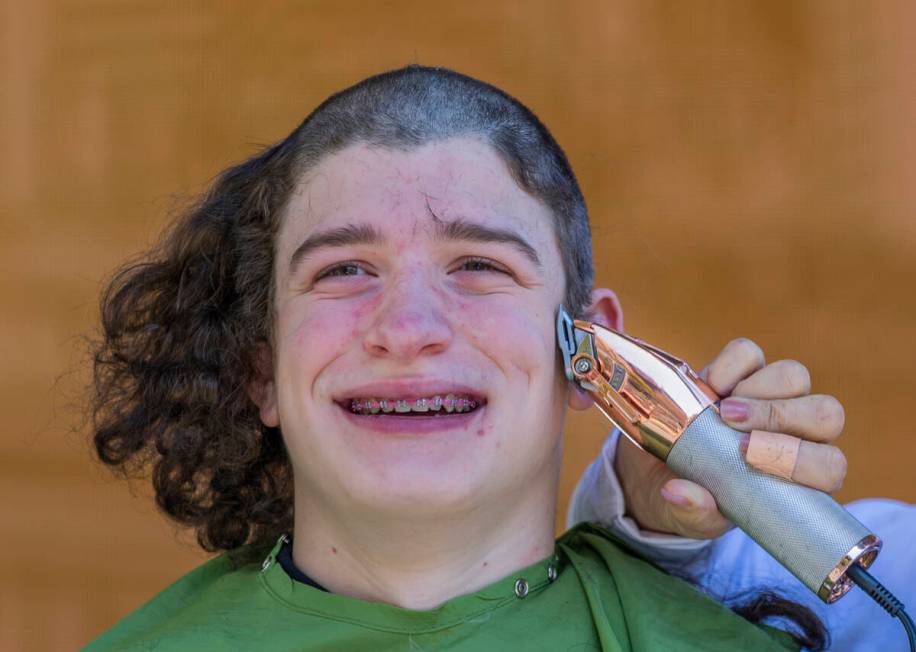 Declan Alvarez with a group from the Clark County Schools has his long hair shaved by a stylist ...