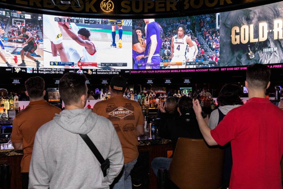 Guests watch on the big screens the first day of the NCAA basketball tournament at the Sports B ...