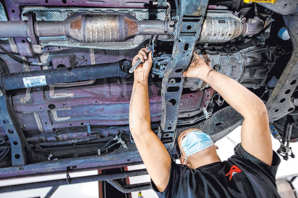 Mechanic Johnny Mejia with Red Rock Repair works beneath a car in November 2020. (L.E. Baskow/L ...