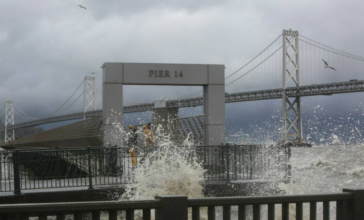 People watch large waves along The Embarcadero near Pier 14 between Mission Street and Howard S ...