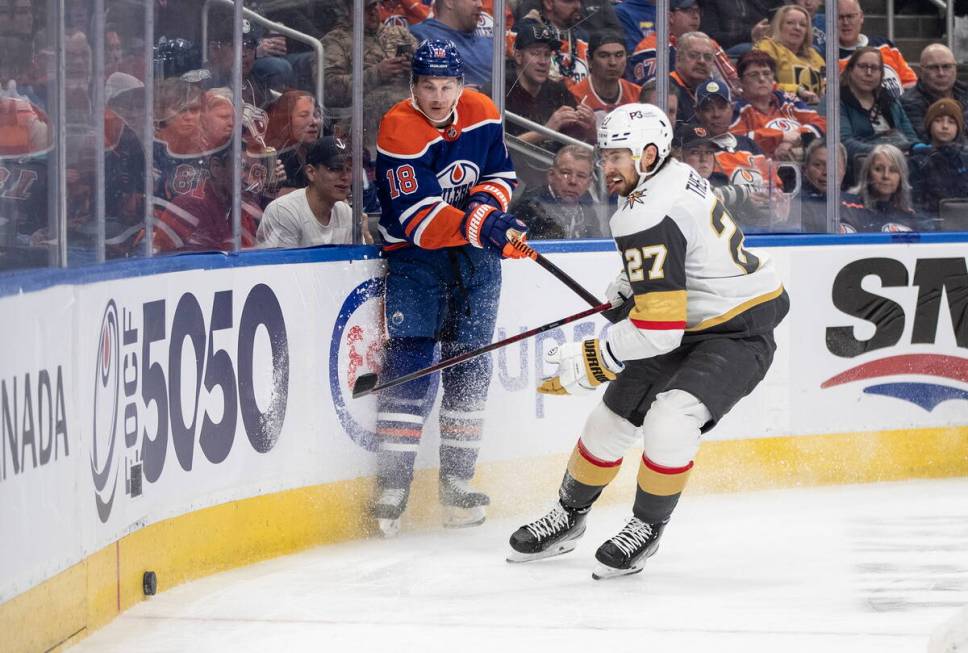 Vegas Golden Knights' Shea Theodore (27) and Edmonton Oilers' Zach Hyman (18) compete for the p ...