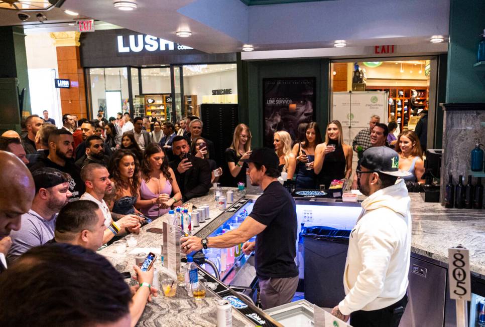 Mark Wahlberg, right, pours drinks at the bar during the opening celebration of a new Wahlburge ...