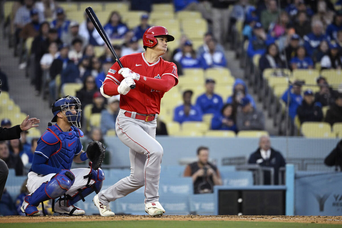 Los Angeles Angels' Shohei Ohtani, right, hits a single as Los Angeles Dodgers catcher Austin B ...