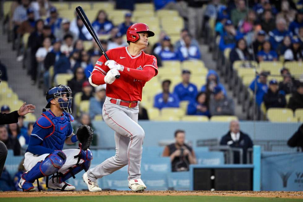 Los Angeles Angels' Shohei Ohtani, right, hits a single as Los Angeles Dodgers catcher Austin B ...