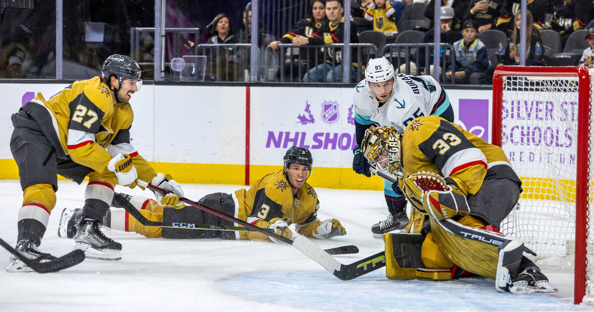 Golden Knights goaltender Adin Hill (33) smothers a puck shot by Seattle Kraken left wing Andre ...