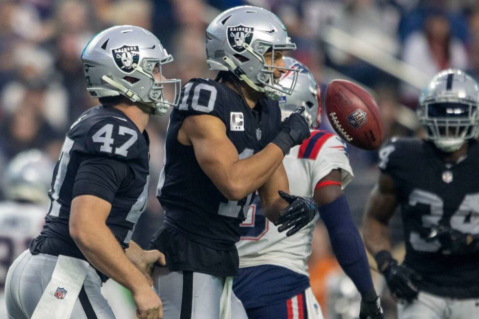 Raiders wide receiver Mack Hollins (10) flips the football and celebrates with long snapper Tre ...