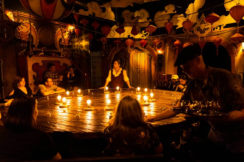 Drinks are passed out as William Bradshaw, center, performs during the The Seance Room at Lost ...
