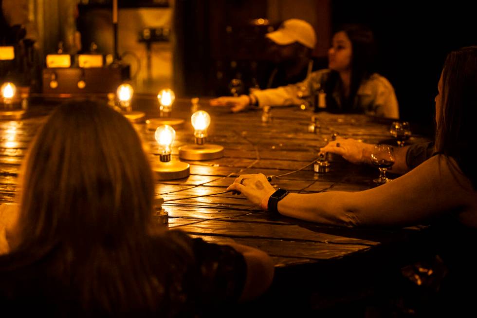 Guests hold onto a copper wire during the The Seance Room at Lost Spirits Distillery on Sunday, ...