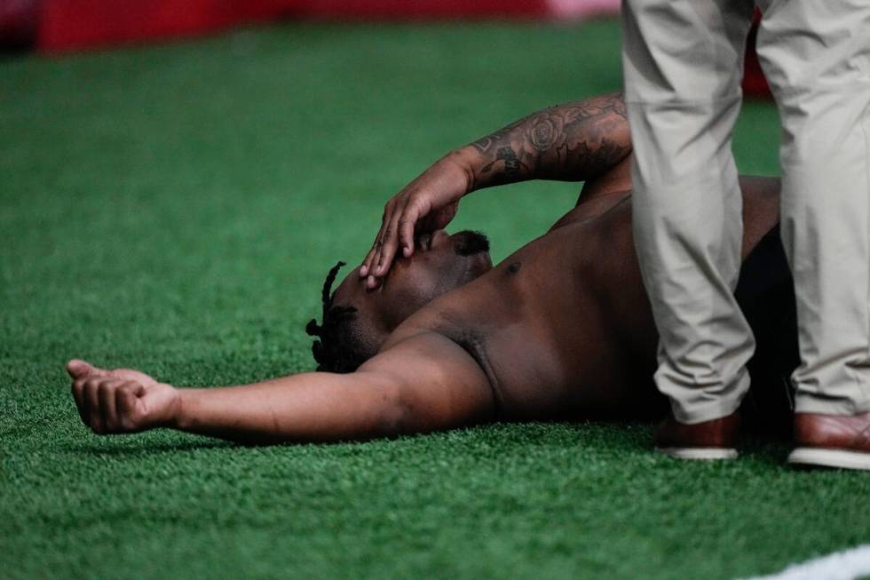 A trainer works with former Georgia defensive lineman Jalen Carter after he runs football drill ...