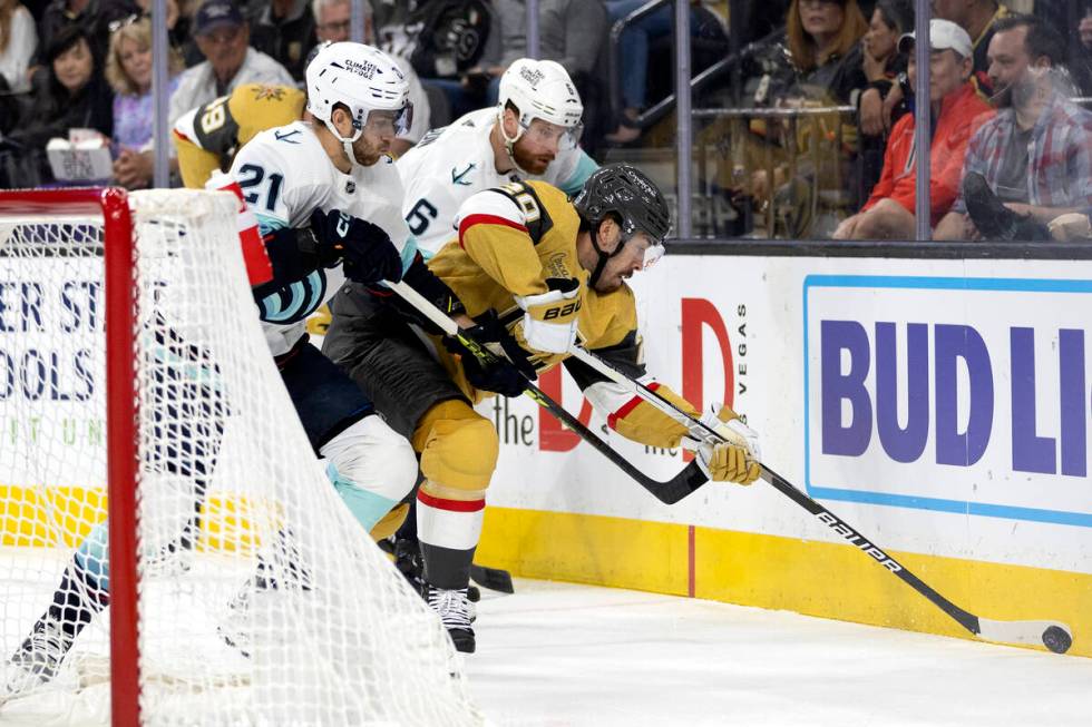 Golden Knights center Chandler Stephenson (20) battles for the puck with Seattle Kraken center ...