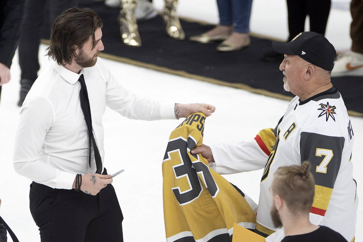 Golden Knights goaltender Logan Thompson hands a signed jersey to a fan on Fan Appreciation Nig ...