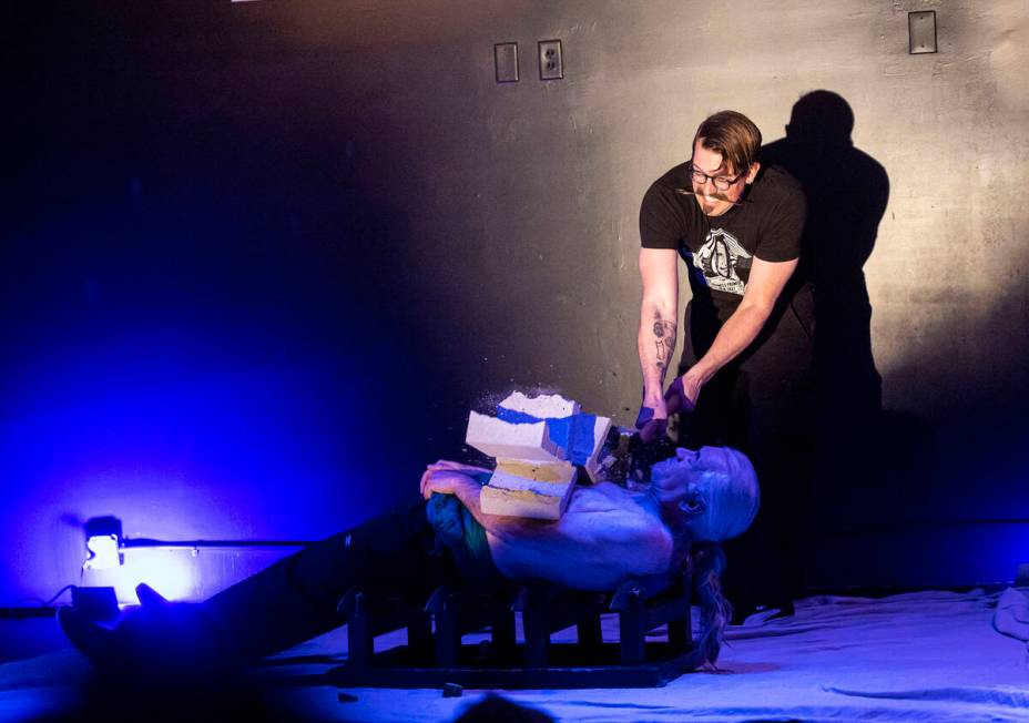 An audience member smashes a cinderblock atop Zamora the Torture King, lying down on blades, du ...