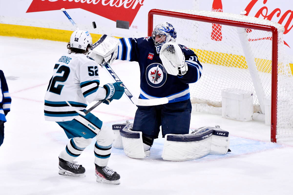 Winnipeg Jets goaltender Connor Hellebuyck, right, makes a save against San Jose Sharks' Triste ...