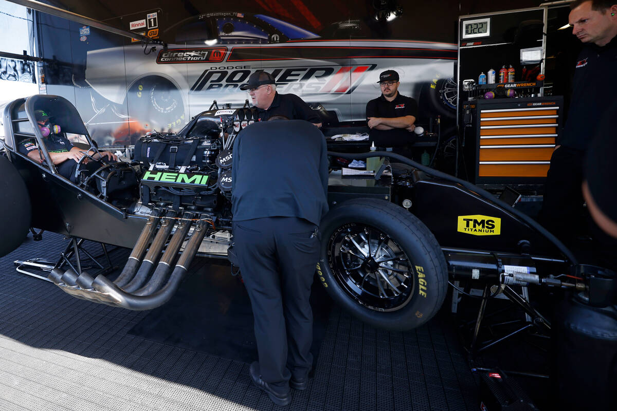 NHRA driver Matt Hagan, left, sits in his funny car as his crew checks the car before the first ...