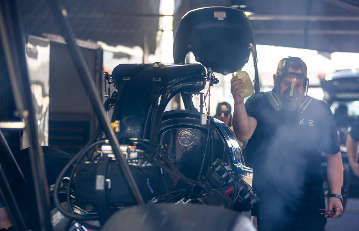 A mechanic with the Funny Car from driver Krista Baldwin fires up the engine in the pit area du ...