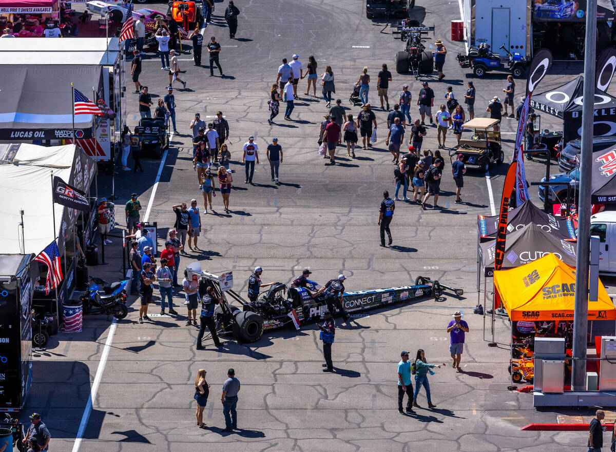 The crew from Top Fuel driver Justin Ashley brings her car out of the pits before a race during ...