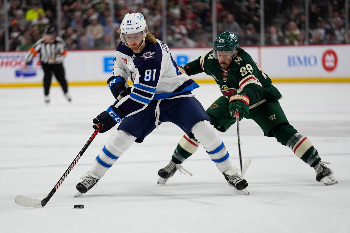 Winnipeg Jets left wing Kyle Connor (81), left, skates with the puck against Minnesota Wild cen ...