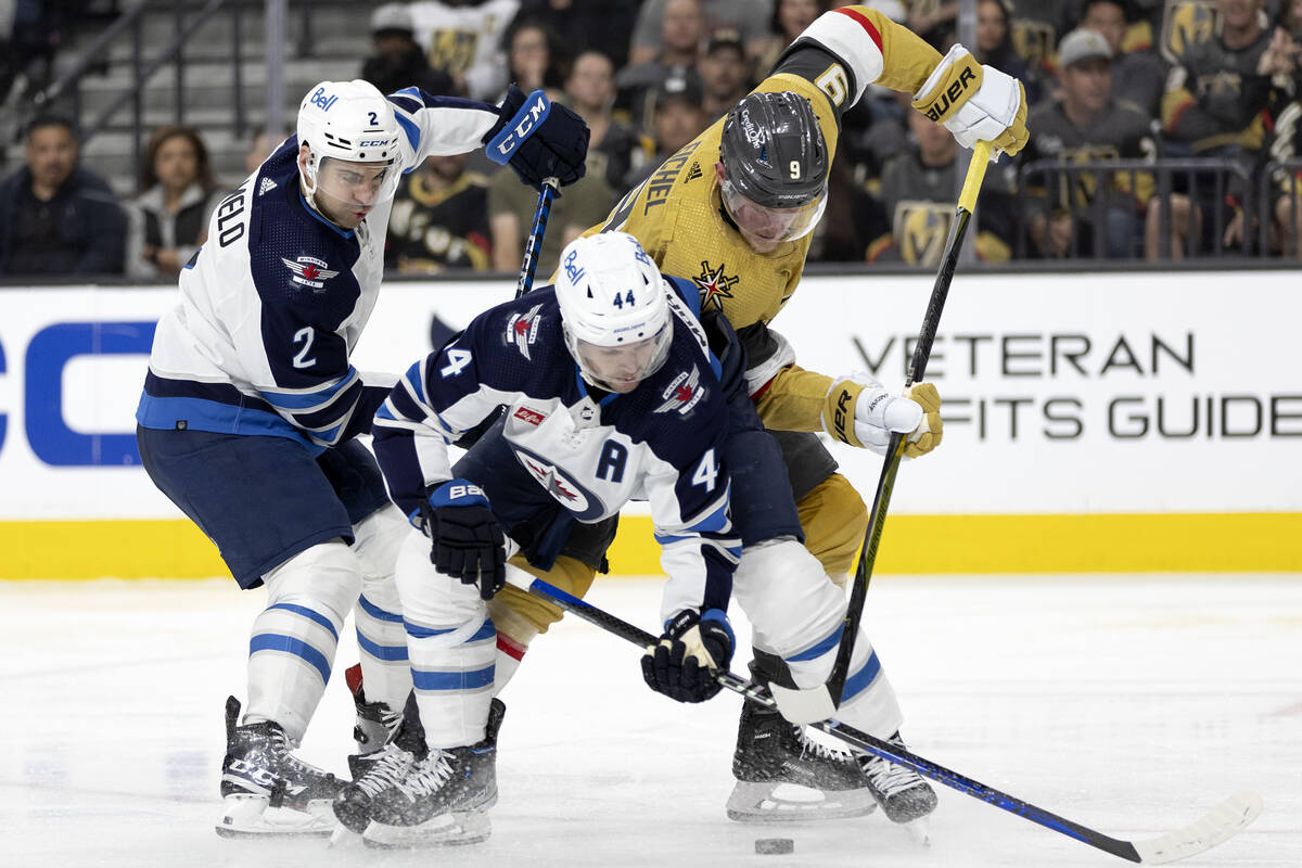 Golden Knights center Jack Eichel (9) battles for the puck against Jets defenseman Dylan DeMelo ...