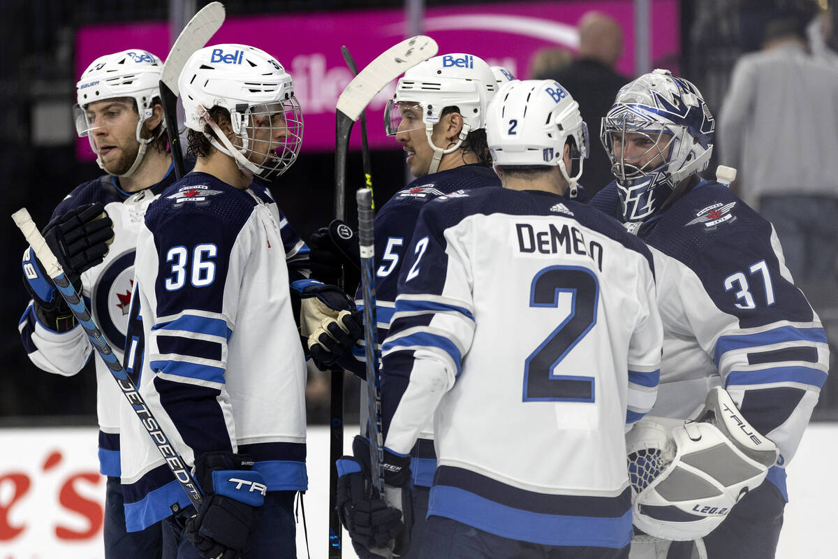 The Jets celebrate around their goaltender Connor Hellebuyck (37) after winning Game 1 of an NH ...