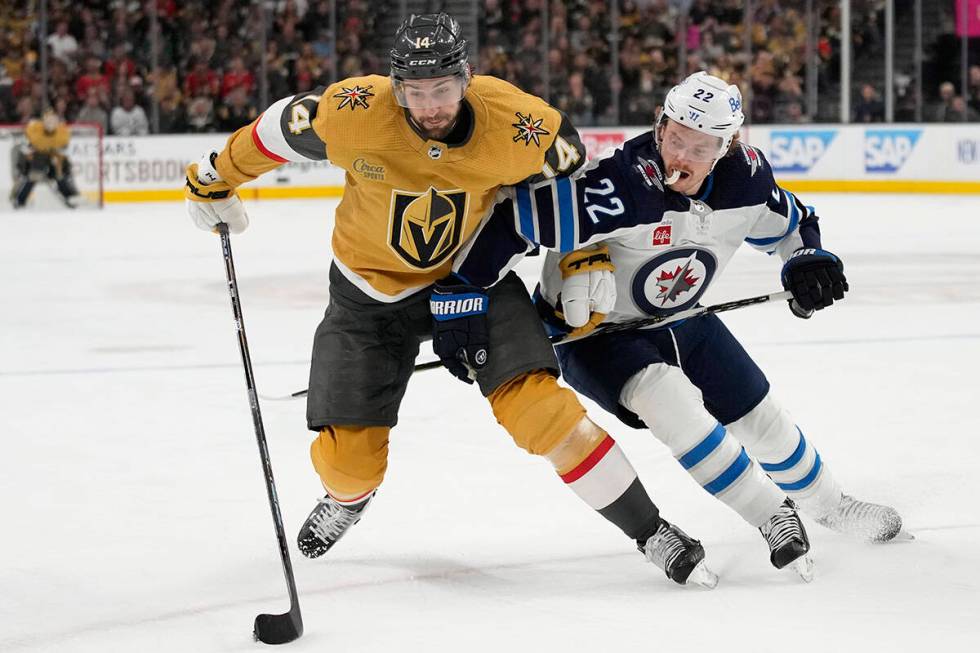 Vegas Golden Knights defenseman Nicolas Hague (14) attempts to drive aroud Winnipeg Jets center ...