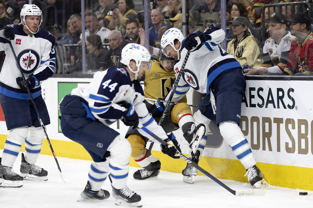 Golden Knights center Brett Howden, center, falls while battling for the puck with Winnipeg Jet ...