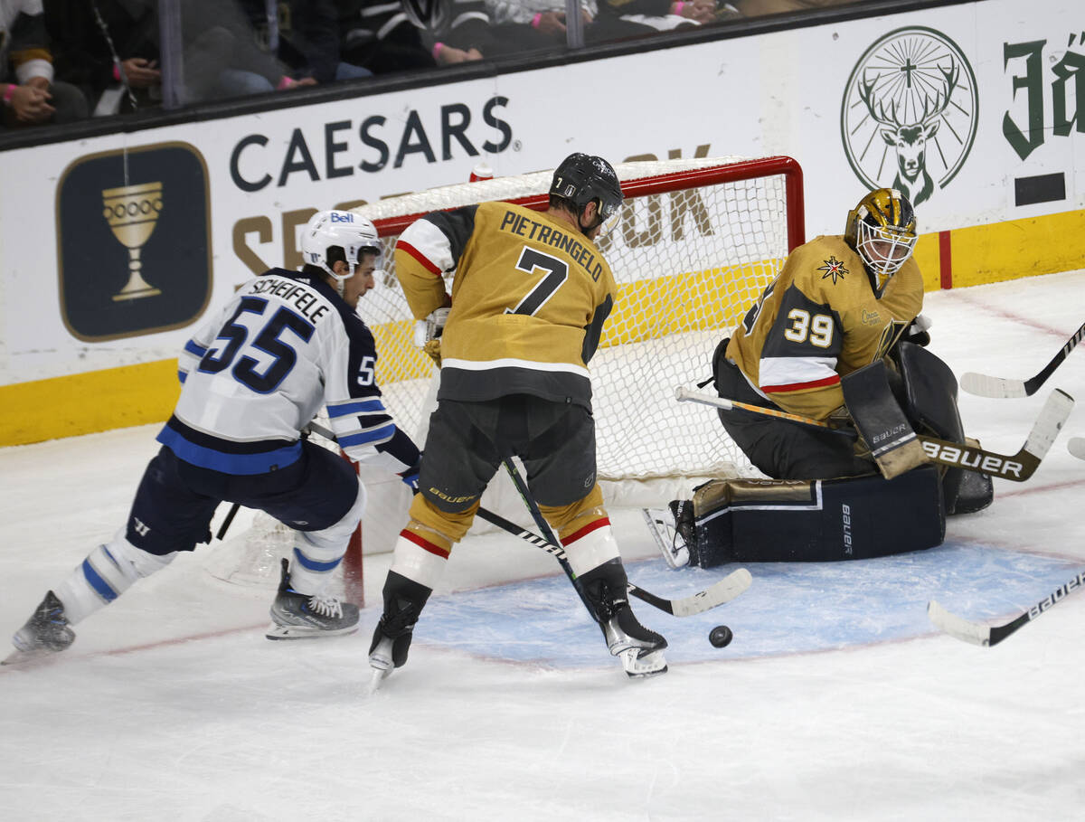 Winnipeg Jets center Mark Scheifele (55) tries to shoot as Golden Knights defenseman Alex Pietr ...