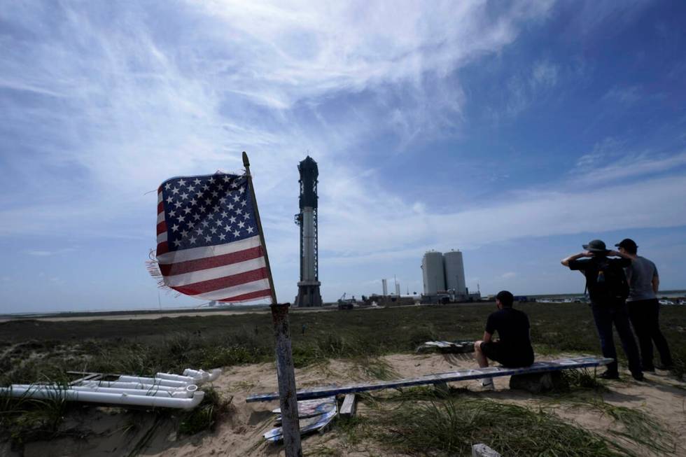 Onlookers watch as SpaceX's Starship, the world's biggest and most powerful rocket, stands read ...