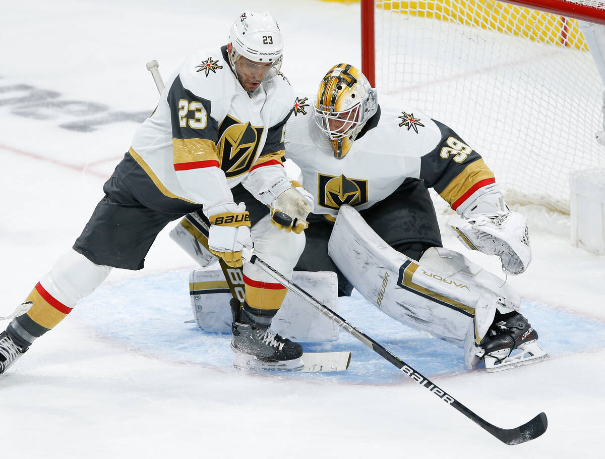 Vegas Golden Knights' Alec Martinez (23) saves a shot in front of goaltender Laurent Brossoit ( ...