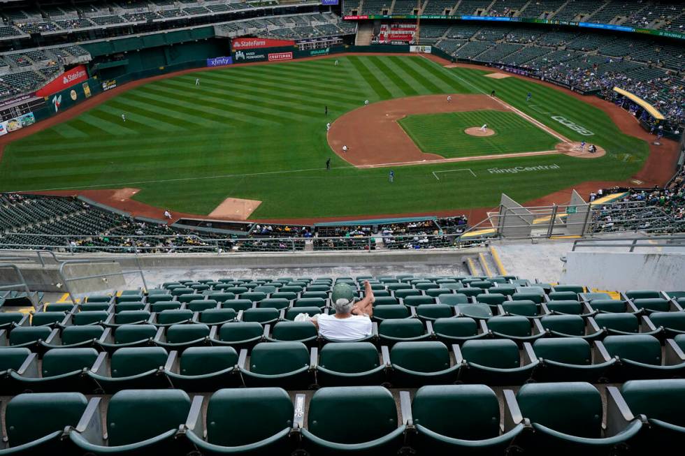 A fan sitting in the upper deck at RingCentral Coliseum watches a baseball game between the Oak ...