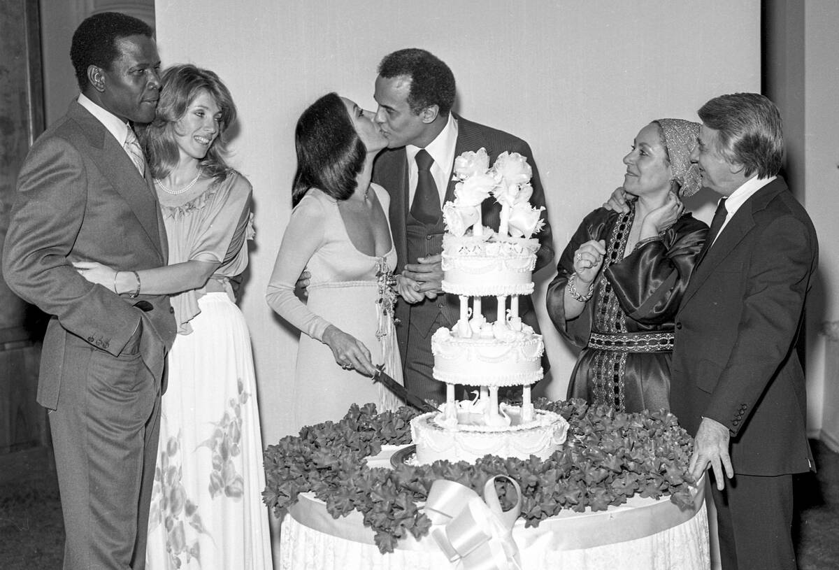 Harry Belafonte and wife Julie Robinson kiss while cutting their wedding cake on Jan. 25, 1976, ...