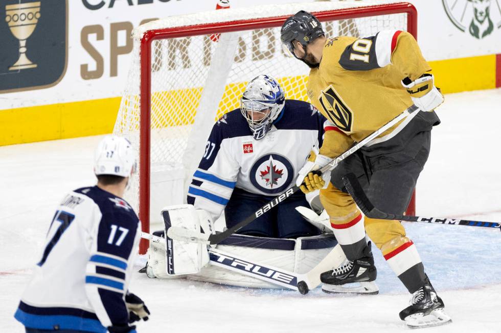 Winnipeg Jets goaltender Connor Hellebuyck (37) saves the puck while Golden Knights center Nico ...