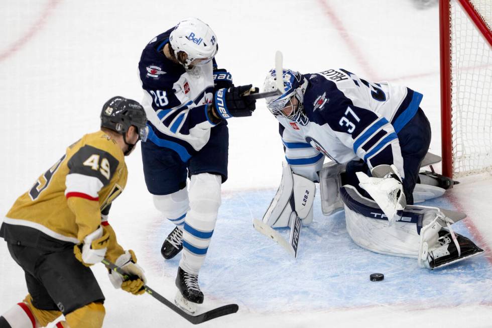 Winnipeg Jets goaltender Connor Hellebuyck (37) saves the puck against Golden Knights center Iv ...