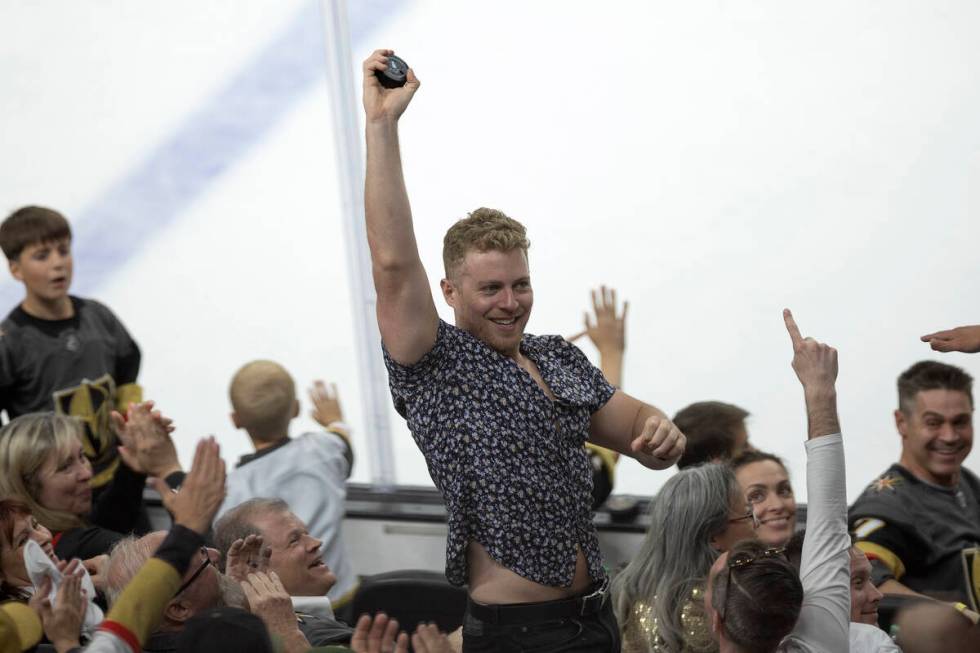 A Golden Knights fan holds up a stray puck during the third period in Game 5 of an NHL hockey S ...