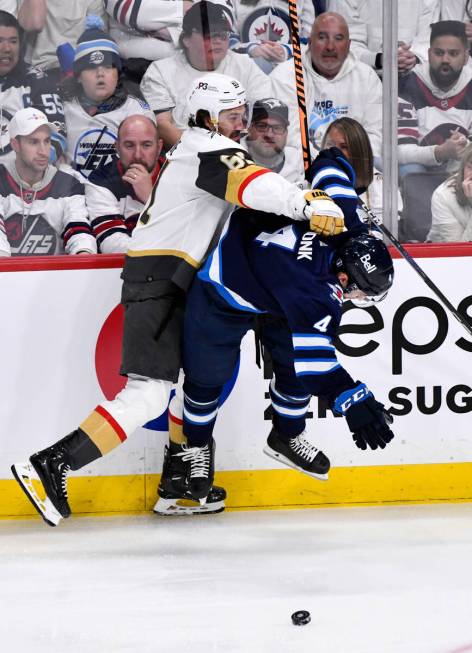 Vegas Golden Knights' Mark Stone (61) checks Winnipeg Jets' Neal Poink (4) during first-period ...