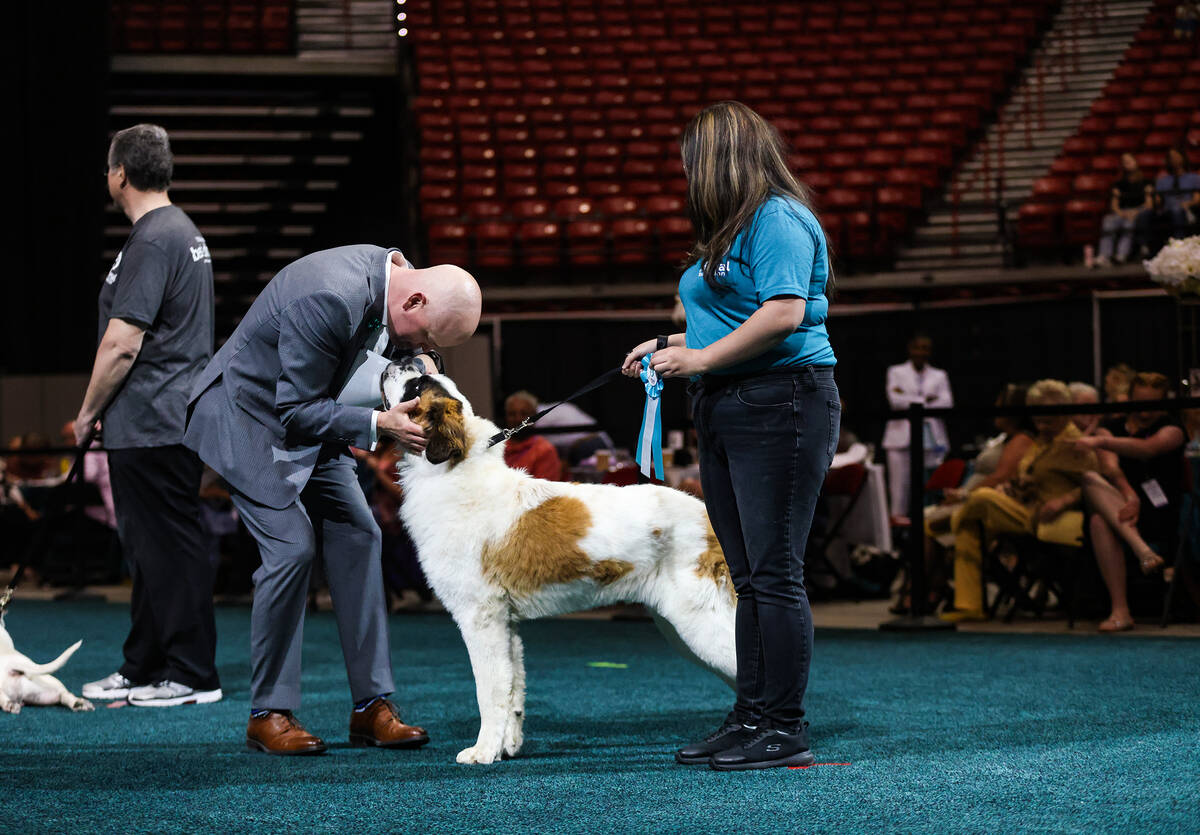 Host Chet Buchanan pets Chief, who won first place in the big dog category, next to volunteer C ...